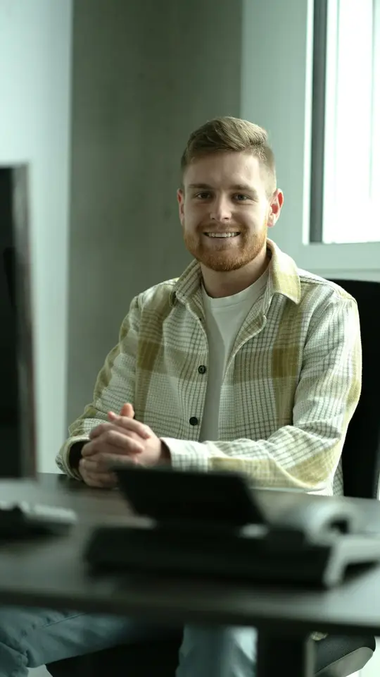 Pol, sentado en su mesa de trabajo, sonriendo.