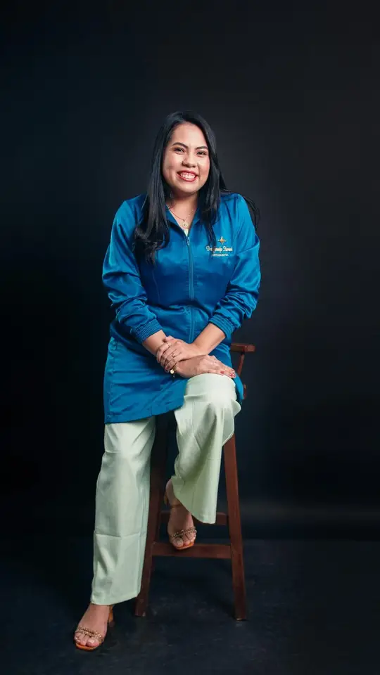 Mar, con uniforme azul, sentada en un taburete.